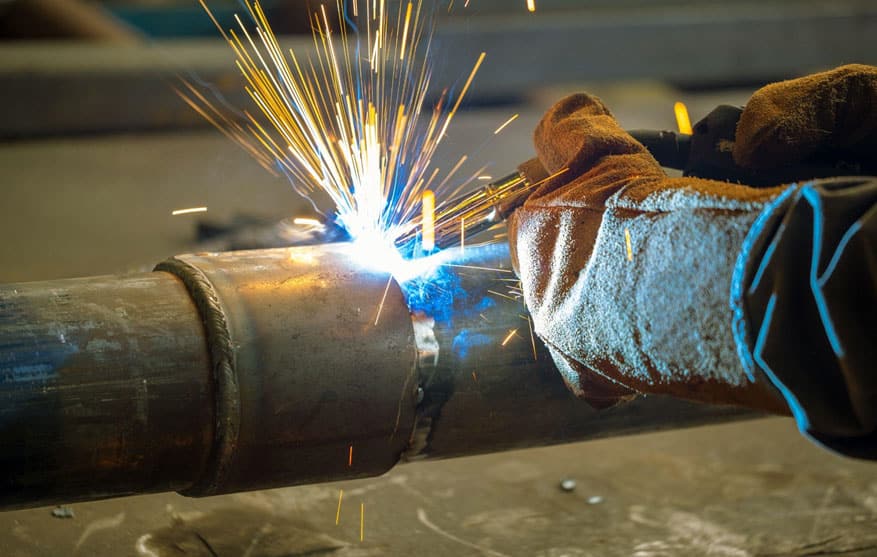 close-up of a welder performing welding on a pipeline