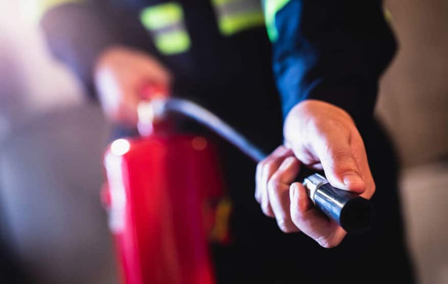 close up of a fire watch professional using a fire extinguisher