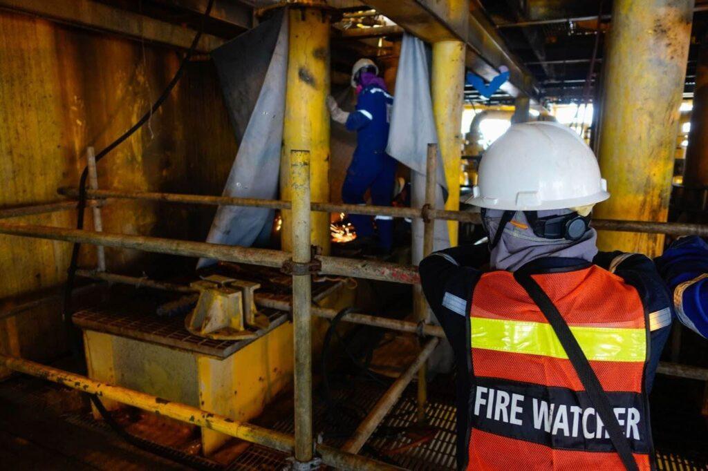 A fire watch guard monitors a construction worker during the renovation of an existing building