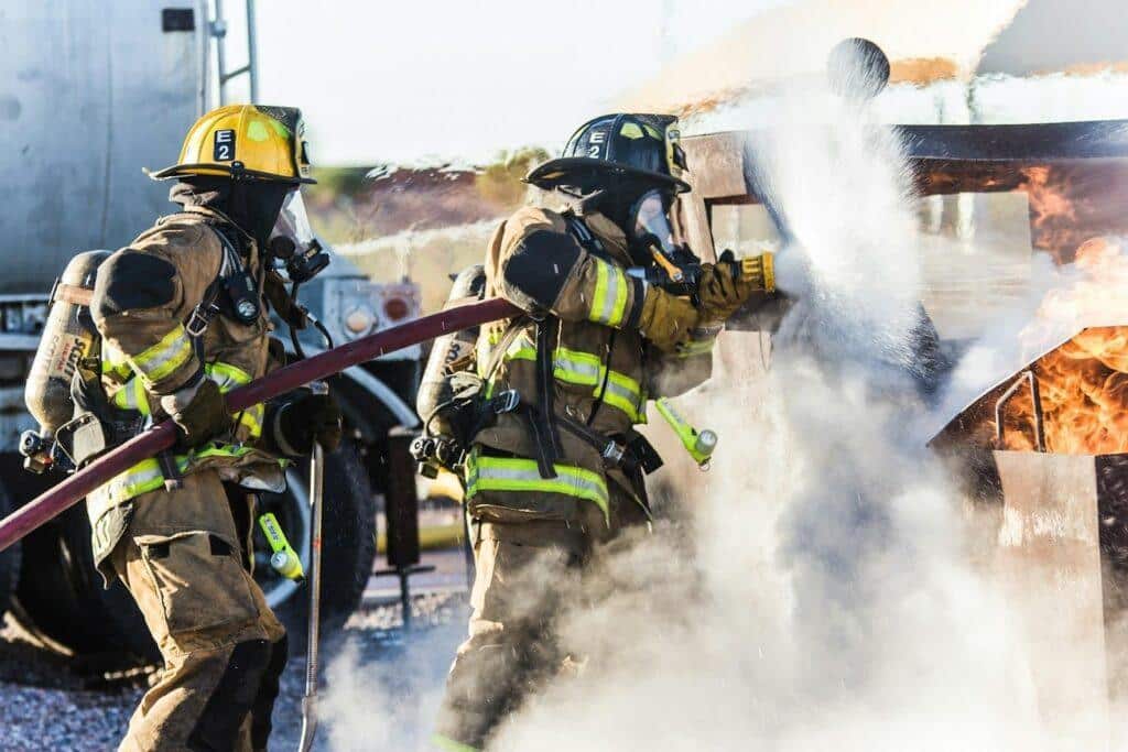 Two firefighters battle a construction fire with a high-pressure hose