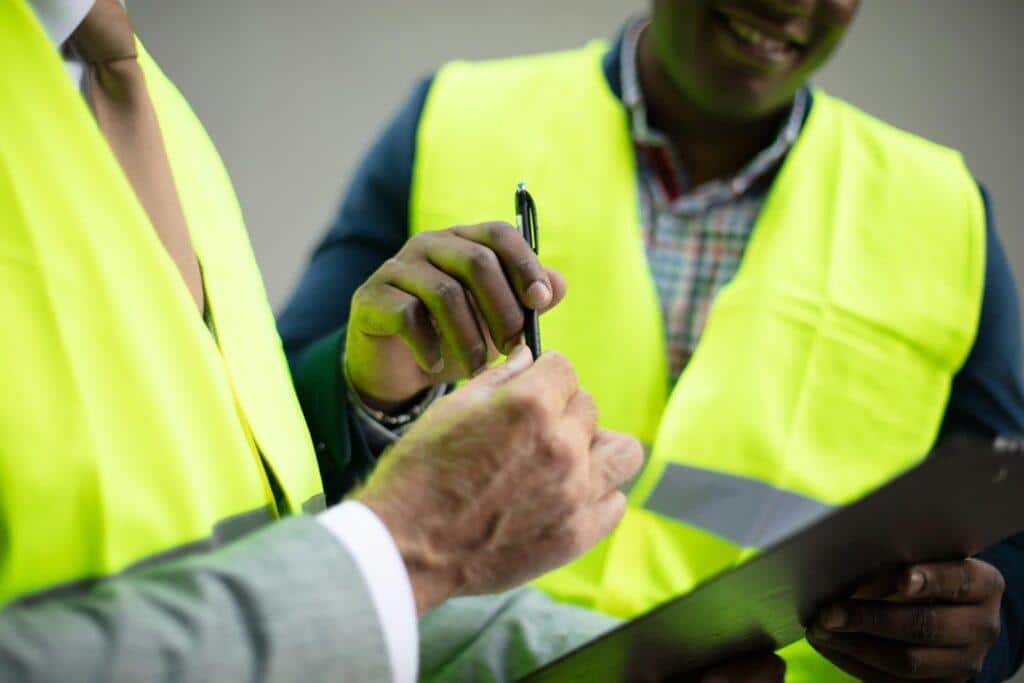 Two men in Hi-Vis jackets on a construction site signing documentation