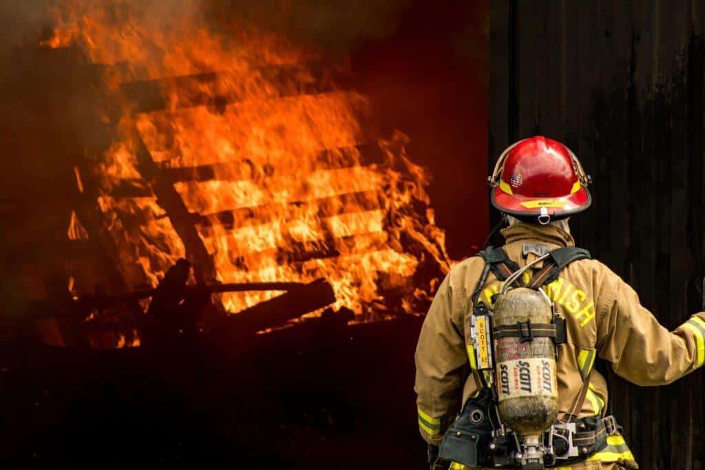 A firefighter looks on at a burning pile of debris inside a building