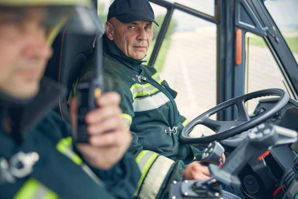 A firefighter leader sits in the truck watching his team take a call