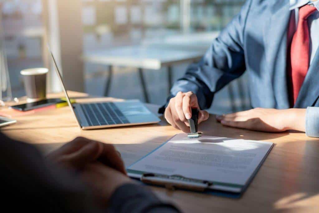 A desk worker stamps a new certification held on a clipboard