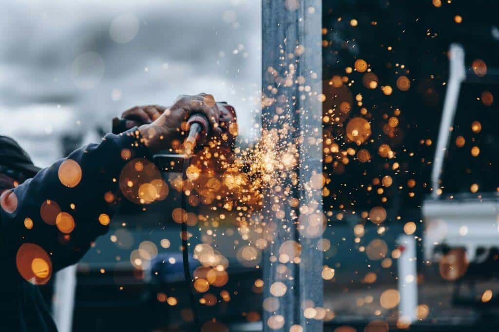 A close-up of a construction worker angle grinding a steel beam