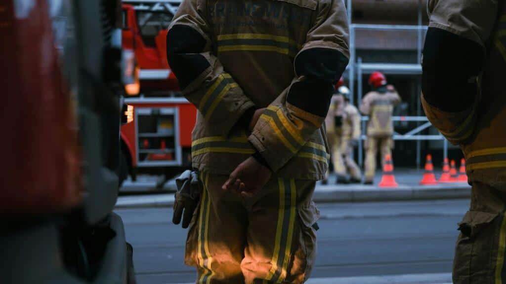 A group of firefighters stand in a line with their hands behind their backs
