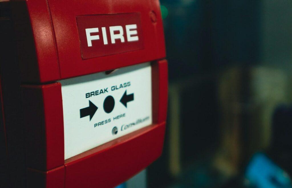 A close-up of a traditional red fire alarm break glass here unit