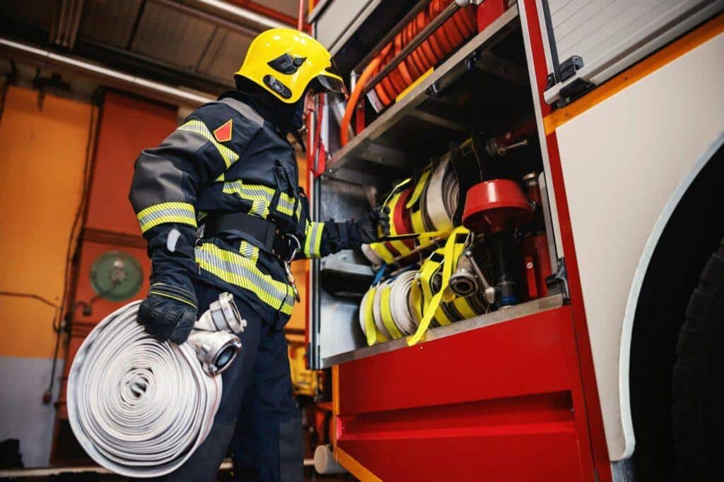 A fire watch firefighter loads up equipment in the fire truck while in uniform