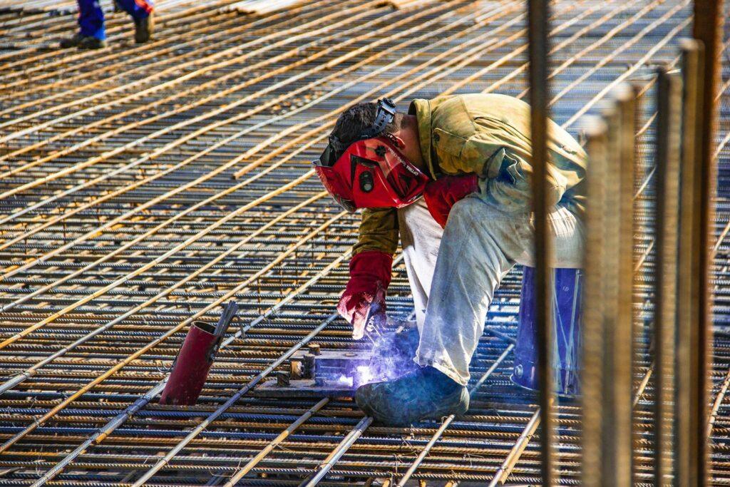 A man welds on the roof of a construction site in protective gear